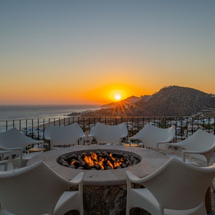Breathtaking sunset views over the sea and mountains create the perfect backdrop for gathering around this cozy fire pit.