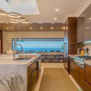 This gourmet kitchen invites you to cook with ocean views, featuring marble countertops, modern appliances, and open flow to the dining area—perfect for preparing and sharing meals with your group.