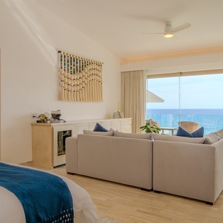 Wake up to endless ocean blues from your spacious suite, where modern comfort meets stunning sea views through floor-to-ceiling windows.