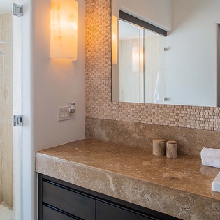 Step into your beautifully appointed bathroom featuring travertine countertops, modern vessel sink, and elegant mosaic tile detailing. The spacious walk-in shower offers a refreshing retreat after a day of exploring.