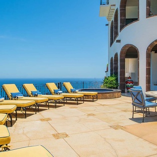Stretch out on vibrant yellow loungers while soaking in breathtaking ocean panoramas from your private terrace, complete with cozy seating for sunset cocktails.