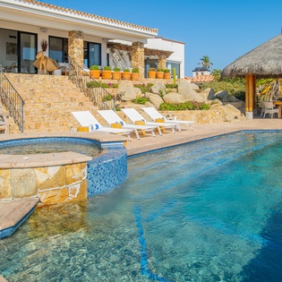 Dive into your private oasis with crystal-clear waters and a relaxing hot tub, all framed by stunning stone architecture and tropical charm.