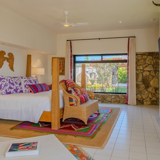 Step into your serene sanctuary where vibrant textiles meet modern comfort. Unwind in your cozy sitting area while garden views frame your peaceful retreat.