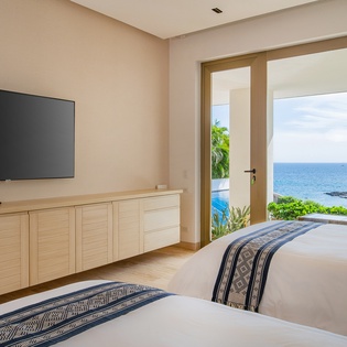 Wake up to endless ocean views from your twin beds, where tropical breezes drift through open doors to your private seaside terrace.