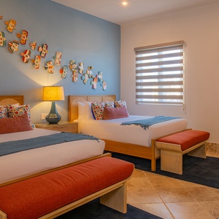 Unwind in your vibrant twin bedroom, where colorful wall art and cozy textiles create a cheerful retreat for restful nights.