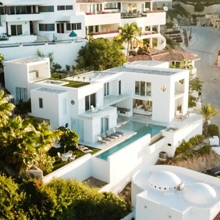 Modern white villa with private pool nestled among tropical palms in an exclusive residential area.