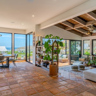 Step into your sunlit oasis where modern comfort meets natural beauty. Floor-to-ceiling windows frame stunning lake and mountain vistas, while warm terracotta tiles and rustic wood beams create an inviting atmosphere for relaxing.