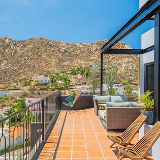 Elevated terrace overlooking hillside neighborhood with mountain backdrop, featuring comfortable outdoor seating and lush potted greenery for relaxed enjoyment of panoramic vistas.