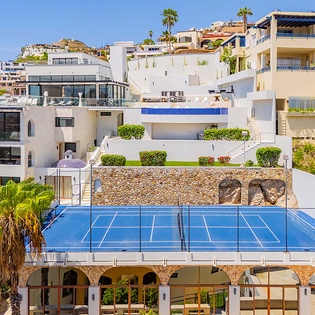 This hillside property features terraced architecture with a private tennis court, multiple pools, and lush tropical landscaping throughout the tiered levels.