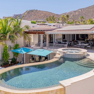 Luxurious hillside villa nestled in a scenic mountain resort area, featuring a stunning multi-level pool and spacious outdoor living spaces for relaxation.