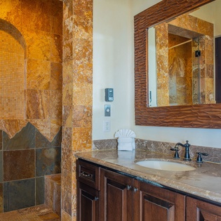 Step into your luxurious stone bathroom featuring golden travertine walls and an elegant walk-in shower with arched alcove details.