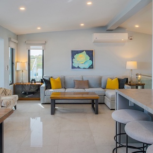 Relax in your stylish open-plan living space with cozy seating, modern artwork, and natural light streaming through large windows.