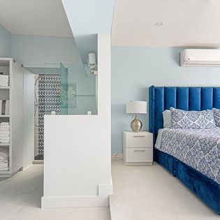 Unwind in your serene bedroom sanctuary with plush blue velvet headboard, crisp linens, and thoughtful storage solutions.