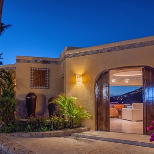 Beautiful villa exterior featuring warm architectural details and lush tropical landscaping at twilight.