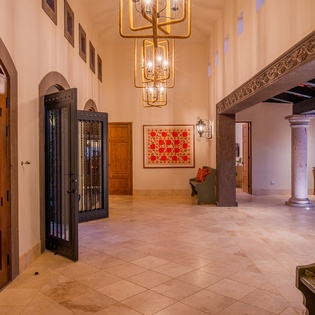 Step into this grand entrance hall where ornate ceiling fixtures cast warm light over rich stone floors and handcrafted archways welcome you home.
