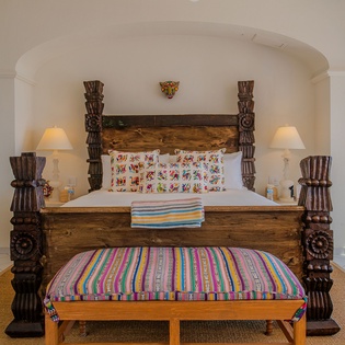 Sink into your carved wooden four-poster bed surrounded by vibrant Mexican textiles and authentic artisan details.