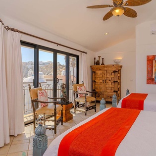 Your bright bedroom features two comfy beds, vibrant artwork, tropical ceiling fan, and sliding doors opening to your private balcony with scenic views.