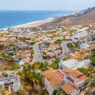 A stunning coastal community nestled between rolling hillsides and pristine sandy beaches, where palm-lined streets wind through charming residences with sparkling ocean waters just beyond.