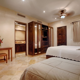 Relax in your spacious bedroom featuring two comfortable beds, rich wood furnishings, and an ensuite bathroom. Cool off with ceiling fan comfort and enjoy the warm, welcoming atmosphere.