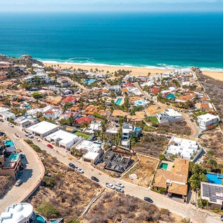 Stunning aerial view of a coastal community nestled between pristine golden beaches and the endless blue Pacific Ocean.