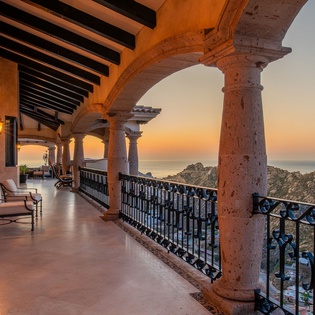 Unwind on your private terrace as warm lanterns cast a golden glow over breathtaking ocean views during sunset.