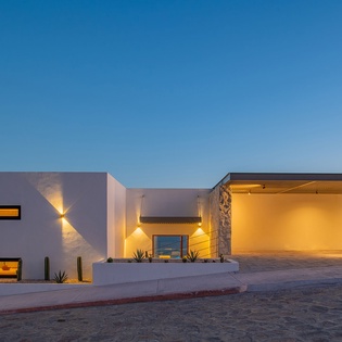 Modern luxury villa showcases striking architectural design with warm evening lighting against clear desert skies.