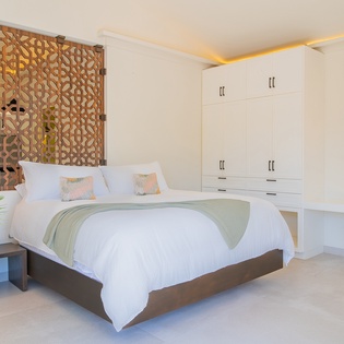 Drift into blissful sleep in your serene sanctuary, where crisp white linens meet warm wood accents and tropical plants create your perfect retreat.