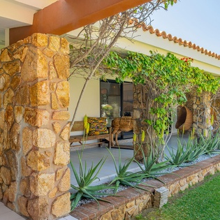 Natural stone architecture and lush greenery create a peaceful Mediterranean atmosphere at this charming property entrance.