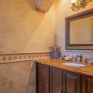 Indulge in your private spa-like retreat with hand-painted tiles, rustic wood vanity, and warm golden lighting creating the perfect ambiance for relaxation.
