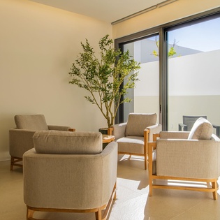 Unwind in your serene living space where comfortable armchairs and natural light create the perfect spot for morning coffee or evening relaxation.