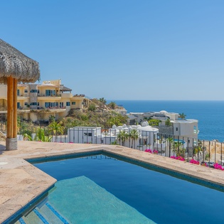 A stunning oceanfront pool terrace overlooking coastal homes and endless blue waters, perfect for relaxation.
