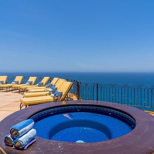 The rooftop hot tub overlooks endless ocean views, with sunbeds lined up for pure relaxation under brilliant blue skies and warm sunshine.