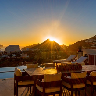 Stunning golden sunset illuminates the hillside terrace, creating a magical backdrop for evening gatherings around the elegant outdoor dining area.