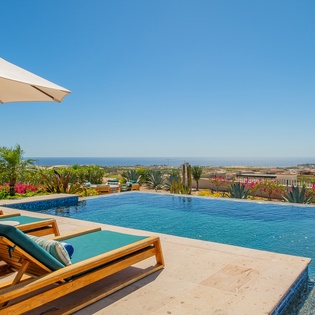 Infinity pool with ocean views and luxurious loungers surrounded by tropical landscaping.