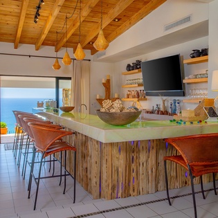 Your kitchen island overlooks stunning ocean views through floor-to-ceiling windows, creating the perfect spot for morning coffee.