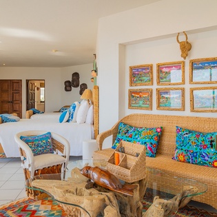 Your spacious suite blends vibrant artwork with wicker furnishings, creating a colorful tropical retreat where comfort meets authentic local charm.