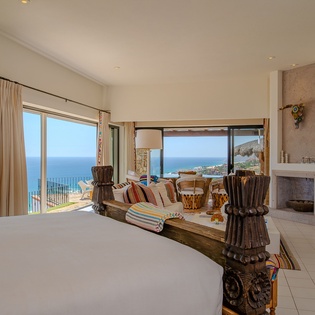 Wake up to stunning ocean views through floor-to-ceiling windows in your spacious bedroom with fireplace and private balcony access.