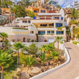 A striking hillside property nestled among tropical palms and native landscaping, offering sweeping views of the surrounding coastal community.