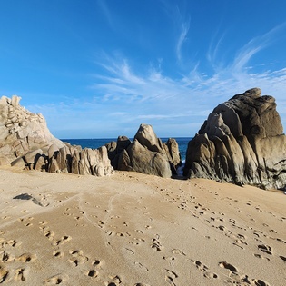 Dramatic granite formations rise from pristine sandy shores, creating a stunning coastal landscape with turquoise waters and sculptural rock towers.