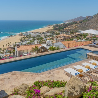 Stunning oceanfront property featuring infinity pool with panoramic views of pristine beaches and dramatic coastal mountains.