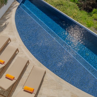 Dive into your own private paradise with this stunning pool surrounded by lush tropical gardens and comfortable loungers perfect for soaking up the sun.