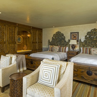 Sink into luxury with ornate carved beds and elegant seating in your beautifully appointed room with rich woodwork and authentic details.