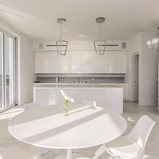 Your sleek modern kitchen flows seamlessly into the dining area, where natural light streams through floor-to-ceiling windows as you enjoy meals.