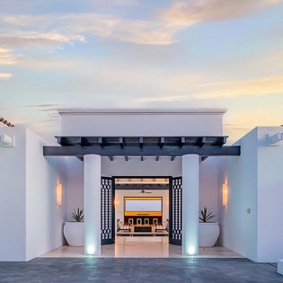 Modern Spanish-style architecture welcomes guests with elegant lighting and a dramatic sunset backdrop, setting the stage for your arrival experience.