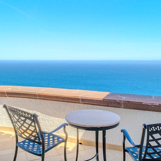 A private terrace overlooking endless blue ocean and sky—the horizon stretches before this peaceful retreat where morning coffee feels extraordinary.