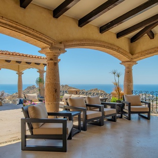 Relax in your elegant covered terrace where comfortable lounge seating invites you to soak in breathtaking ocean views framed by stunning arched architecture.