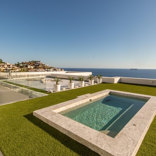 Modern rooftop terrace with private pool overlooking Mediterranean coastline and charming hillside village.