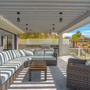 Your private terrace awaits with plush seating and outdoor kitchen, where ocean breezes meet modern comfort under tropical skies.