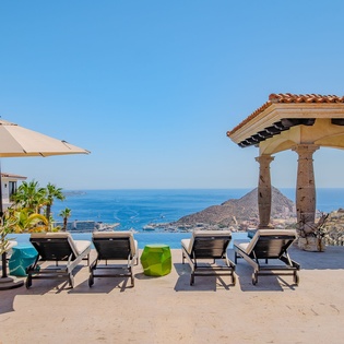 Stunning oceanfront terrace with infinity pool, elegant gazebo, and panoramic sea views across the coastline.