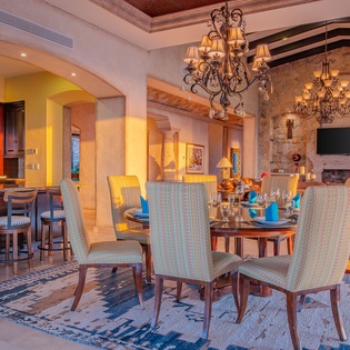 Gather around your elegant dining table where rustic beams meet refined chandeliers, creating the perfect backdrop for memorable meals and conversations.